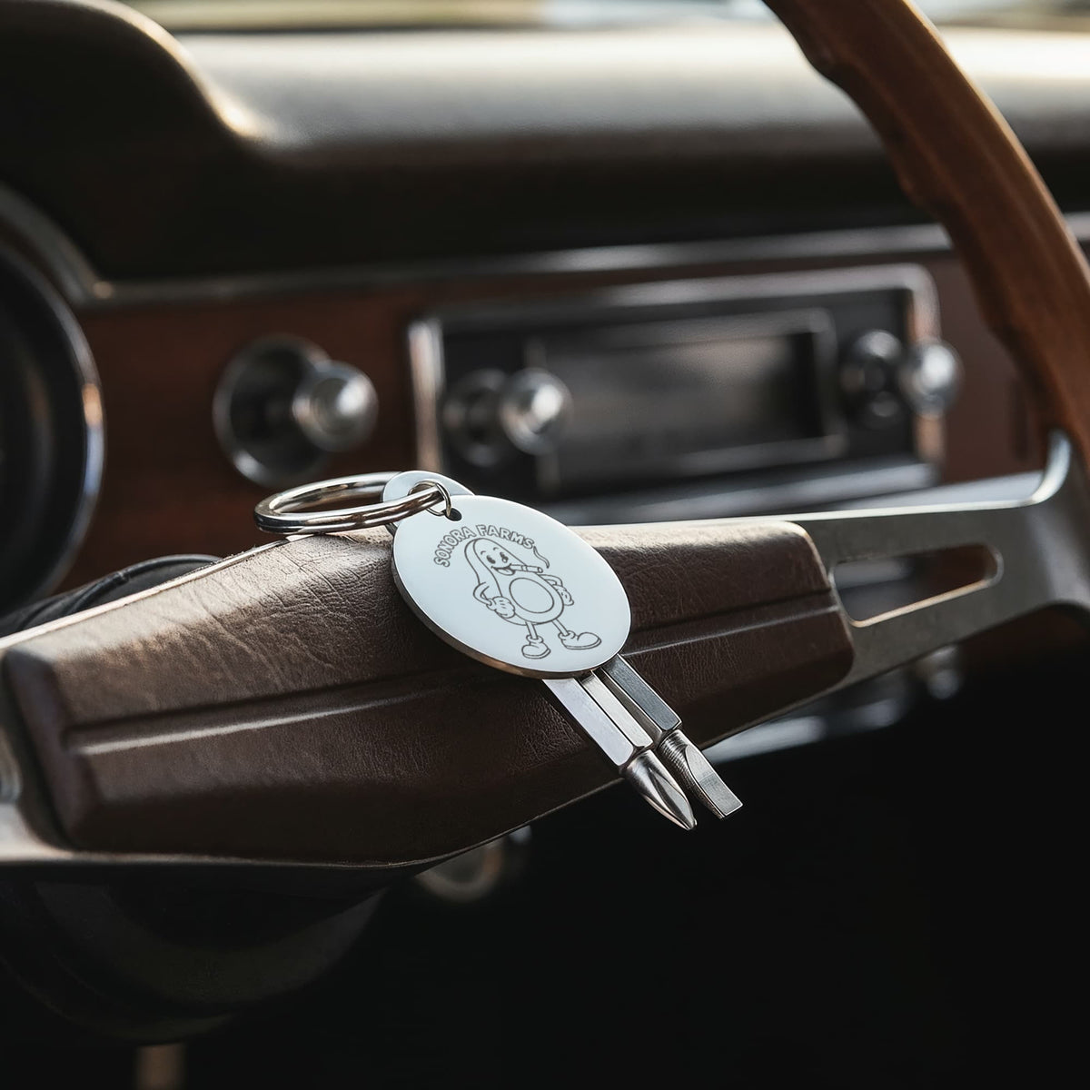 Silver engraved screwdriver keychain displayed on a vehicle steering wheel